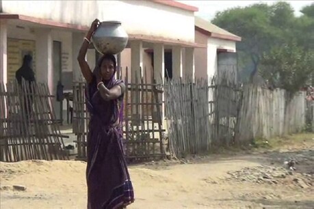पास के गांव से पानी लाती एक आदिवासी महिला