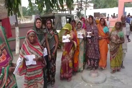 बिहार के गोपालगंज में एक पोलिंग बूथ पर मतदान के लिए कतारबद्ध महिलाएं