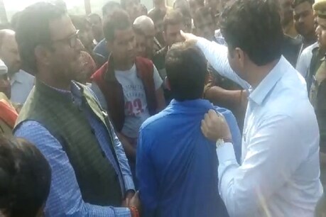 अमेठी के डीएम प्रशांत कुमार मृतक सोनू सिंह के चचेरे भाई का गिरेबान पकड़े हुए.
