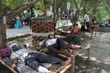बुखार के बाद सड़क पर खाट बिछाकर लोग इलाज कराते हुये.