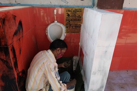 टाइल्स पर सफेद पेंट लगाते कर्मी
