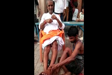पूर्व प्रधान का पैर धोता युवक.