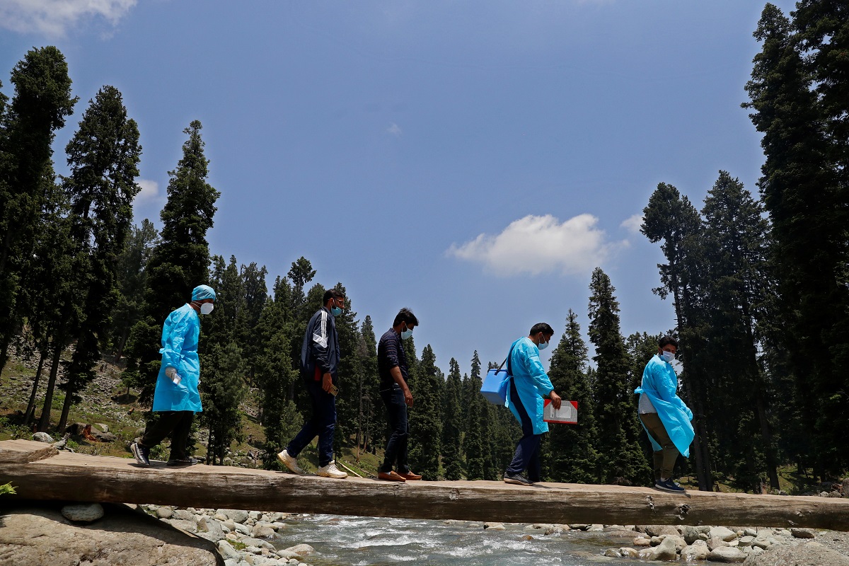  7 जून, 2021 को स्‍वास्‍थ्‍यकर्मी पैदल चलकर जम्‍मू कश्‍मीर के पुलवामा जिले के दुर्गम इलाकों में लोगों को वैक्‍सीन लगाने पहुंचे थे. (REUTERS/Danish Ismail)