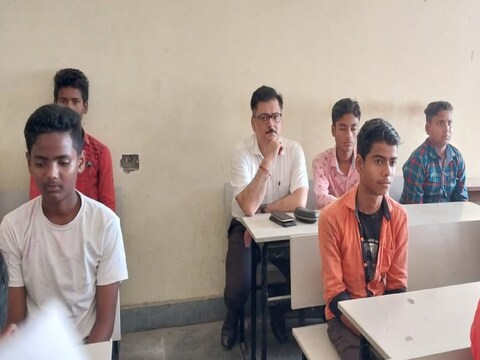 कटिहार के कलेक्‍टर उदयन मिश्रा (सफेद शर्ट में) चुपके से फिजिक्‍स की क्‍लास में छात्रों संग बैठ गए. (न्‍यूज 18 हिन्‍दी)