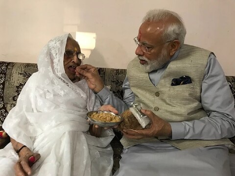 प्रधानमंत्री नरेंद्र मोदी अपनी मां हीरा बा के 100वें वर्ष में प्रवेश करने के मौके पर उनका मुंह मीठा कराते हुए. (ANI Photo)