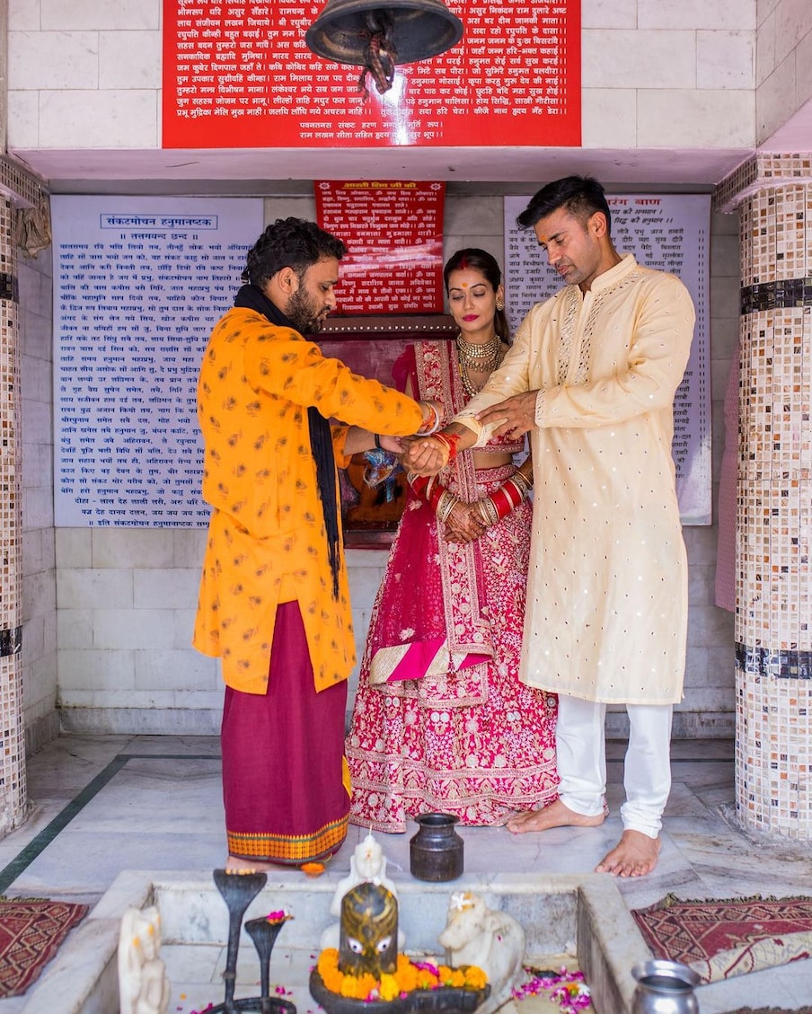  इस फोटो में नवविवाहित जोड़े को मंदिर के अंदर पूजारी से कलावा बंधवाते हुए देखा जा सकता है.  (PHOTO Credit: @ sangramsingh_wrestler Instagram)
