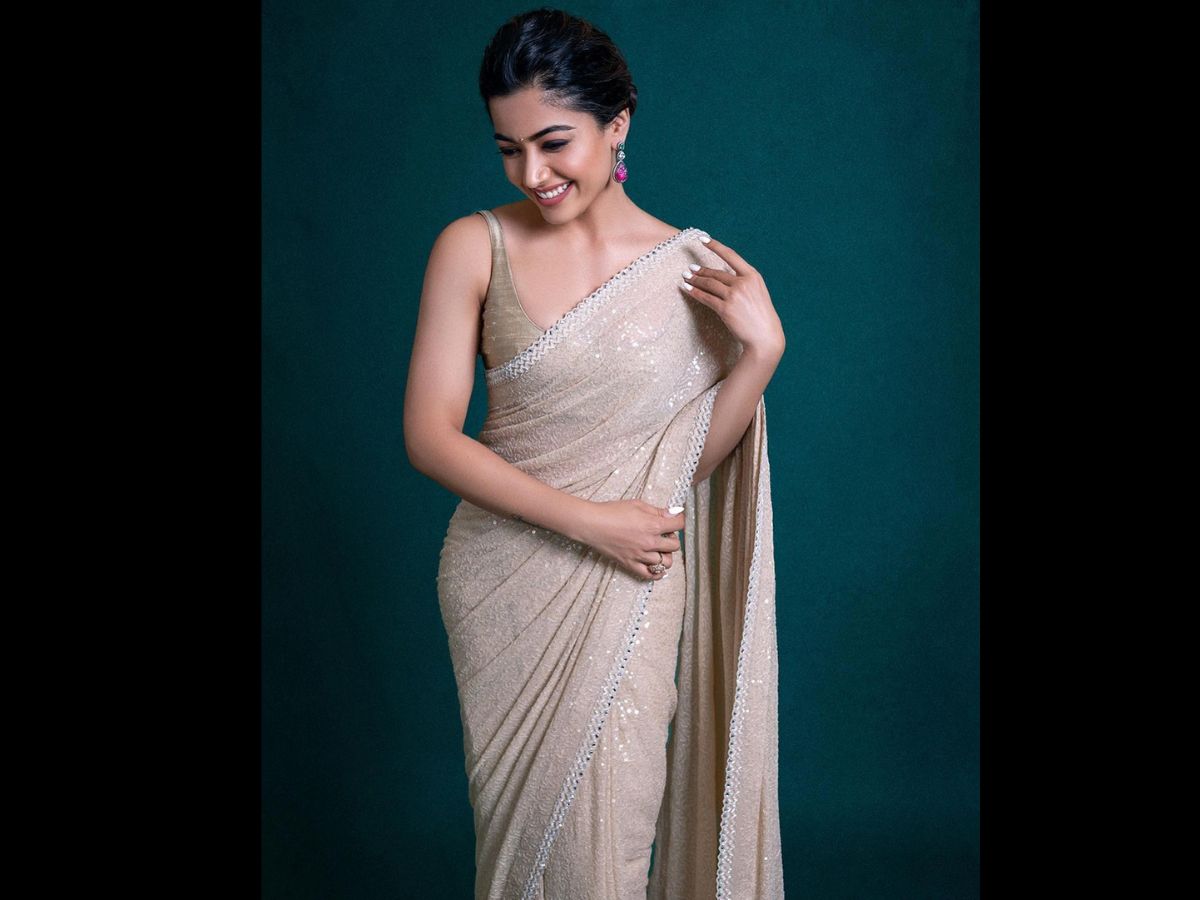  ऑफ वाइट रंग की ये सिक्‍वेंसिंग साड़ी भी आप किसी भी ओकेजन में स्‍टाइल कर सकती हैं. वाइट बेस पर वाइट वर्क और वाइट बॉर्डर इस साड़ी को और भी क्‍लासी लुक दे रहा है. इसके साथ आप आई मेकअप और ब्राइट लिप कलर ट्राई कर सकती हैं. रश्मिका ने यहां कलरफुल स्‍टोन वाले ईयररिंग पहने हैं और बालों को बांधकर रखा है. Image : Instagram/Rashmika Mandanna