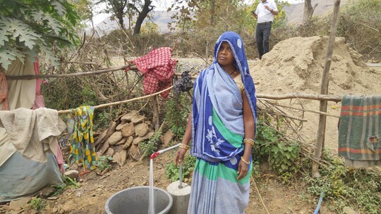 नल से जल भरती ग्रामीण महिला.