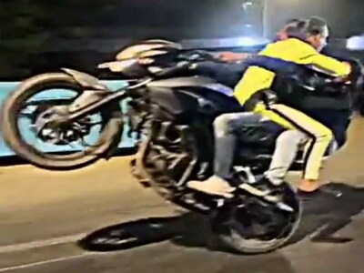 सोशल मीडिया पर वायरल हुई क्लिप में, एक आदमी अपने सामने बैठी एक महिला के साथ व्हीली का प्रदर्शन करता हुआ दिखाई दे रहा है और दूसरी पीछे बैठी है. (Screengrab)