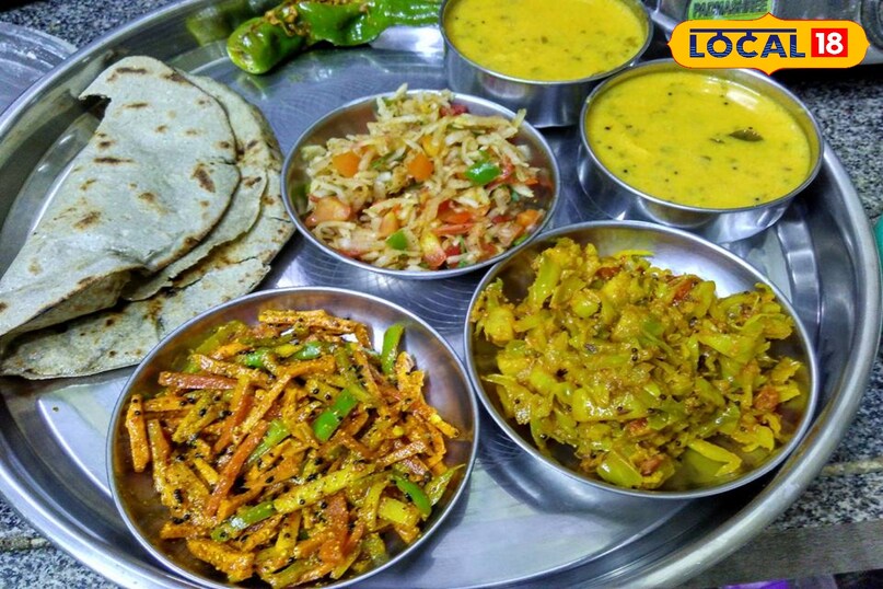 राजस्थान की पारंपरिक बाजरा थाली अपने देसी स्वाद और पौष्टिकता के लिए जानी जाती है. सर्दियों का मौसम आते ही घर में बाजरे के व्यंजन बनने लगते हैं. बाजरे की थाली न केवल स्वाद का मज़ा देती है, बल्कि सेहत के लिए भी बेहद लाभदायक होती है. इस थाली में बाजरे की बाटी, चटपटी दाल, मिर्च के टिपोरे और बाजरा लड्डू जैसे चारों व्यंजन प्रमुख रूप से शामिल होते हैं. इनके साथ छाछ का गिलास जोड़ देने से खाने का मज़ा और भी बढ़ जाता है, इस थाली का हर पकवान राजस्थान की मिट्टी और परंपरा की खुशबू से भरा होता है. आज की रेसिपी स्पेशल में हम आपको बाजरे की थाली में शामिल व्यंजनों के बारे में बताएंगे.