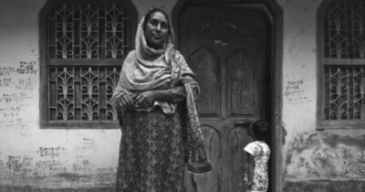 भागलपुर दंगे में पीड़ित महिला अपने घर के दरवाजे पर खड़ी, बच्चा पास में. 