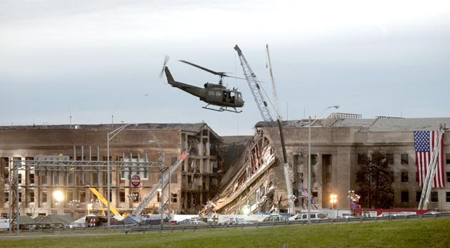 A military helicopter flies in front of the Pentagon September 14, 2001 in Arlington, Virginia at the impact site where a hijacked airliner crashed into the building.