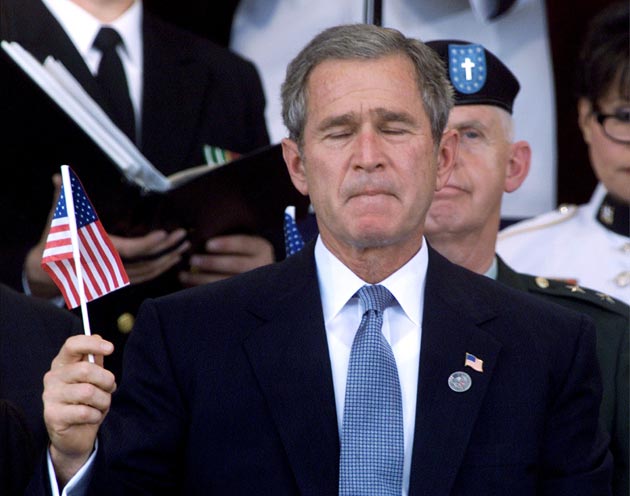 US President George W Bush holds an American flag during a Memorial Service at the Pentagon October 11, 2001 in Arlington, Virginia.