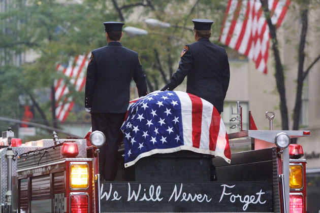 Firefighters stand atop a fire engine with the flag draped casket of fellow fireman Lieutenant Dennis Mojica September 21, 2001 during a funeral service at St Patrick's Cathedral in New York City. Mojica, who was with Rescue Company 1, is one of nearly 300 firefighters who lost their lives in the World Trade Center disaster.