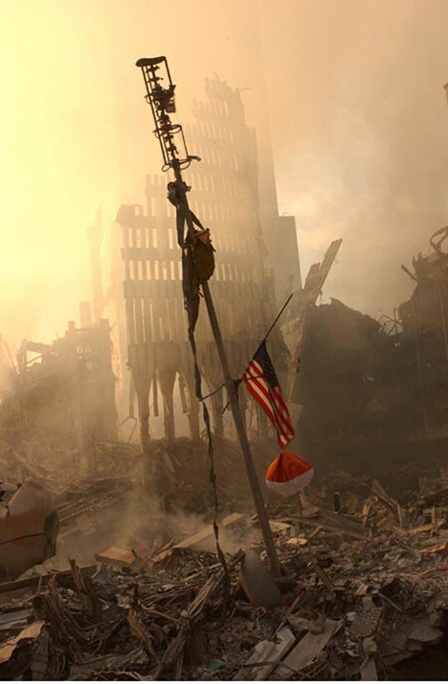 A US flag flies from a television antenna September 13, 2001 amid the rubble of the World Trade Center after an aircraft crashed into it September 11 as part of a terrorist attack. The antenna was once at the top of one of the 110 story twin towers.