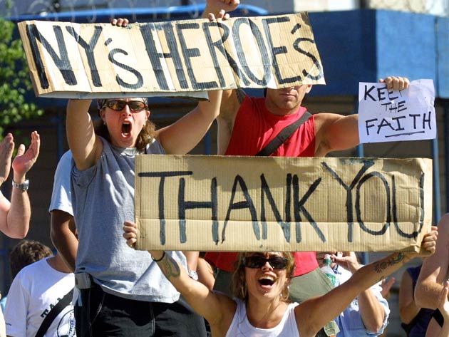 Wellwishers cheer as recovery personnel drive by on their way to the World Trade Center site September 12, 2001 in New York City.