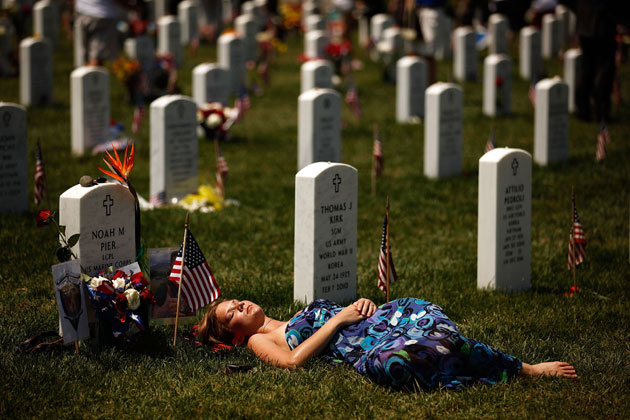 A young woman lays down on the grave of US Marine Corps Lance Corporal Noah Pier on Memorial Day at Arlington National Cemetery May 31, 2010 in Arlington, Virginia. Pier was killed Feburary 12, 2010 in Marja, Afghanistan. This is the 142nd Memorial Day observance at the cemetery.