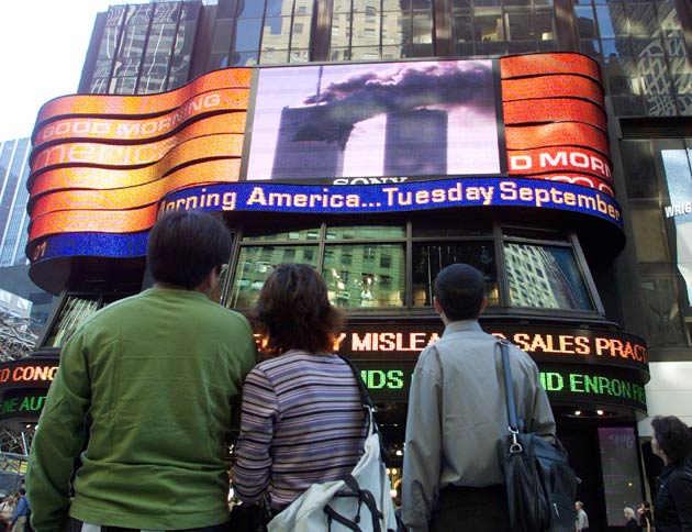 People in Times Square watch the World Trade Center fire live on large screen televisions in New York on September 11, 2001. Two hijacked US commercial planes slammed into the twin towers of the World Trade Center early on Tuesday, causing both 110-story landmarks to collapse in thunderous clouds of fire and smoke.