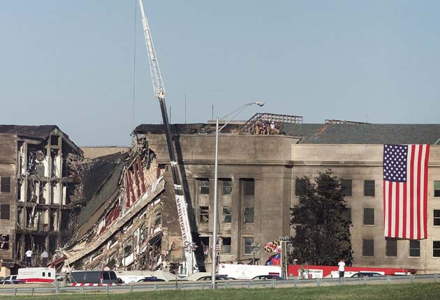 Firemen and rescue workers undraped a large US flag near the damaged area of the Pentagon Building at the US Military Headquarters outside of Washington, September 12, 2001. The Pentagon and the World Trade Center Buildings in New York City were attacked September 11 after terrorists hijacked commercial jetliners and crashed them into the buildings.