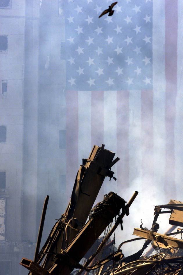 A bird flies over the wreckage of the World Trade Center as a giant American flag hangs from the World Financial Center (rear), September 19, 2001.