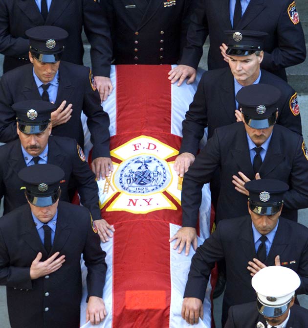 Fire fighters stand by the casket of New York Fire Department Chaplain Rev Mychal Judge, as it leaves his funeral service at St Francis of Assisi Church September 15, 2001. Judge died whilst giving the last rites to a fireman in the aftermath of the collapse of the World Trade Center Towers.