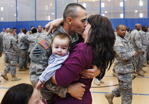 Staff Sergeant Keith Fidler kisses his wife Cynthia, as their son Kolin looks on, during a homecoming ceremony in New York, April 8, 2011 for the New York Army National Guard's 442nd Military Police Company's return from Iraq.