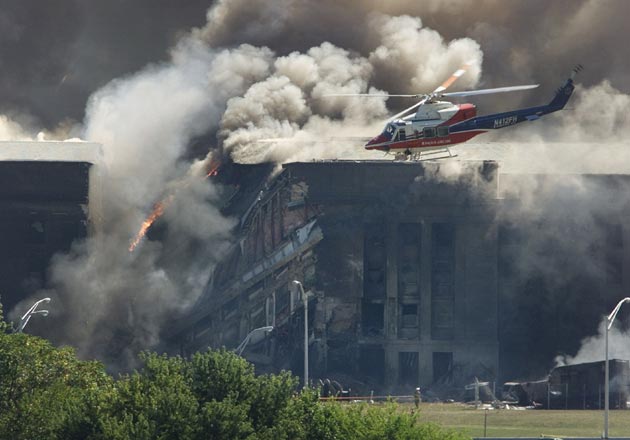 A rescue helicopter surveys damage to the Pentagon as firefighters battle flames after a hijacked airplane crashed into the US military headquarters outside of Washington, in this September 11, 2001 file photo. This year's anniversary of the September 11 attacks in New York and Washington will echo the first one, with silence for the moments the planes struck and when the buildings fell, and the reading of 2,792 victims' names.