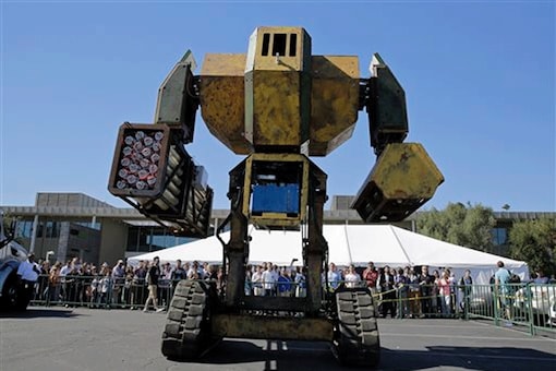 In this photo taken Friday, Oct. 9, 2015, a crowd of people watch the MegaBots 15-foot tall, piloted Mk.II robot in action at the Pioneer Summit in Redwood City, Calif. Let the giant robot wars begin. A team of American engineers challenged a group in Japan to a battle for robot supremacy, and the Japanese said bring it on. So Oakland-based MegaBots has launched a Kickstarter campaign to raise money to turn the Mk.II, into a real fighting machine, ready for hand-to-hand combat. (AP Photo/Eric Risberg)