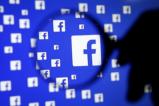 Facebook logo seen through a magnifying glass.