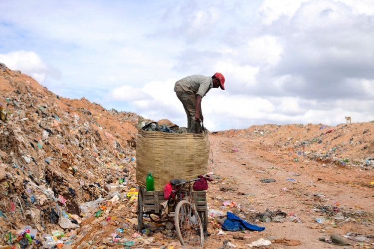 A rag picker prepares to pack a sack filled with recyclable materials at a garbage dump in Bangalore. (Photo: Reuters)