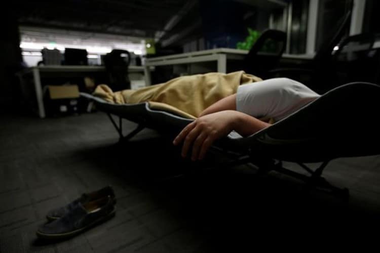 Zhenguo, a system engineer at RenRen Credit Management Co., sleeps on a camp bed after finishing work in Beijing