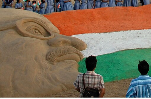 School children gather around a sand sculpture of the Indian national flag and Mahatma Gandhi on the eve of India's Independence Day at a beach in Puri.
(Image: Reuters)
