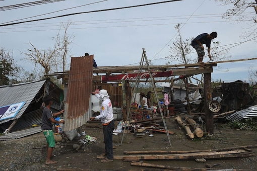 A family fix the roof of their damaged house at the height of typhoon Haima in Ilagan town, Isabela province, north of Manila. (Image: AFP)