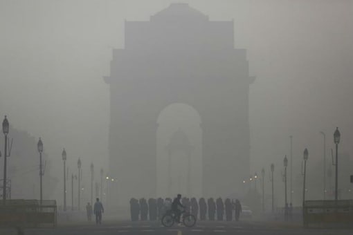 In this file photo,  a man rides his bicycle next to Army Jawans marching in front of India Gate on a smoggy morning in New Delhi.