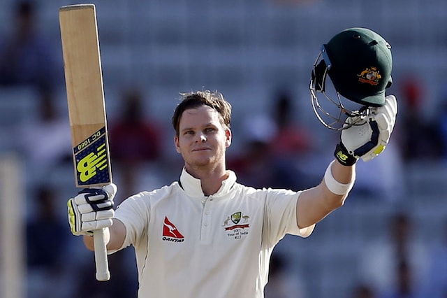 Australia's captain Steven Smith raises his bat and helmet to celebrate scoring a century during the first day of the Ranchi Test. (Ap Photo)