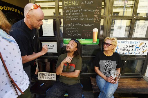 A man talks with smokers sitting in front of The Ponorka (Submarine) Beer Bar, allowed for smokers up to the prior day, in Olomouc on Wednesday. (Photo courtesy: AP)