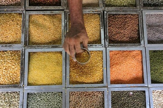 An employee collects lentils from a container inside a grocery store at a residential area in Mumbai. (Reuters) An employee collects lentils from a container inside a grocery store at a residential area in Mumbai. (Reuters)