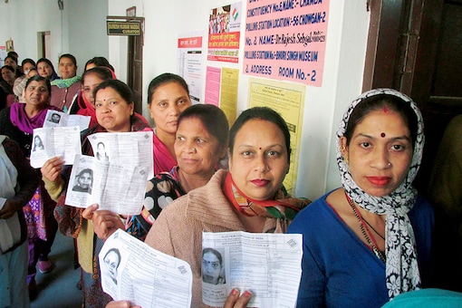 Women voters in a queue show their voter identity card as they wait to cast their vote at a polling booth. (PTI)