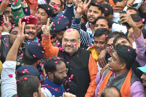 BJP President Amit Shah flashes victory sign as he is accorded warm welcome on his arrival at the party headquarters in New Delhi on Monday, after the party's victory in the Assembly elections in Gujarat and Himachal Pradesh (PTI Photo)