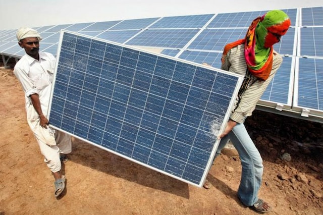 File photo of workers carrying a damaged photovoltaic solar panel at the Gujarat solar park in Charanka village. (Reuters)