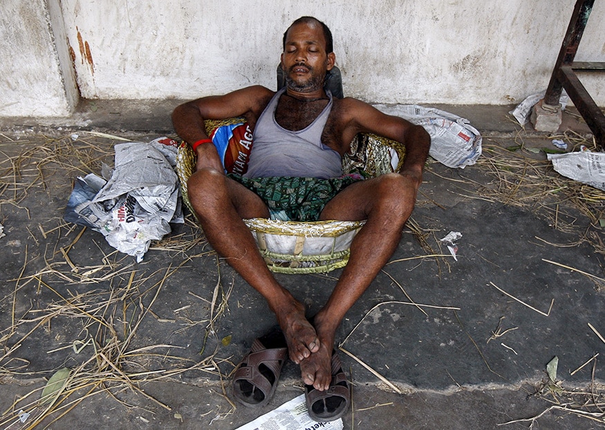 A labourer takes a nap in a basket at a wholesale vegetable market on a hot summer day in Kolkata. (Image: Reuters)