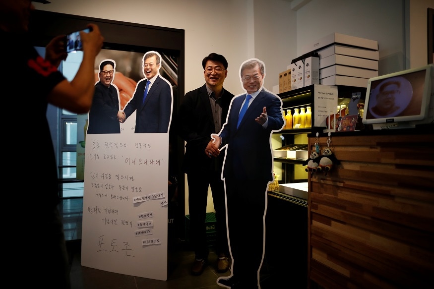 Cafe owner Kim Jeong-il takes photographs of a customer next to cardboard cutouts of North Korean leader Kim Jong Un and South Korean President Moon Jae-in at his coffee shop in Jeonju, South Korea, June 1, 2018. REUTERS/Kim Hong-Ji