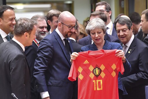 British PM Theresa May, center right, holds up a Belgian National team soccer jersey presented by Belgian Prime Minister Charles Michel, center left, during a round table meeting at an EU summit. (Photo: AP)