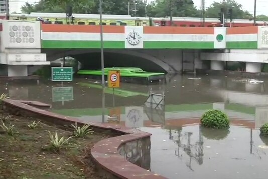 A bus got stuck in a waterlogged road under Minto Bridge following heavy rainfall in the national capital on Sunday morning. (Image: ANI)