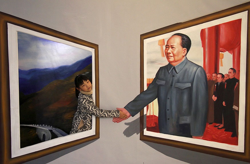 A girl poses for a photograph next to a 3D painting of China's late Chairman Mao Zedong at an exhibition in Binzhou, Shandong province. (Image: Reuters)