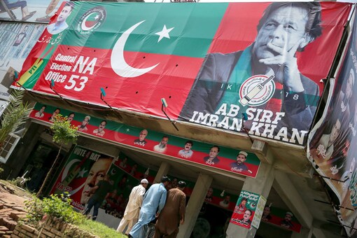 People walk past an image of cricket star-turned-politician Imran Khan, chairman of Pakistan Tehreek-e-Insaf (PTI) at a market in Islamabad, Pakistan. (Image: Reuters)