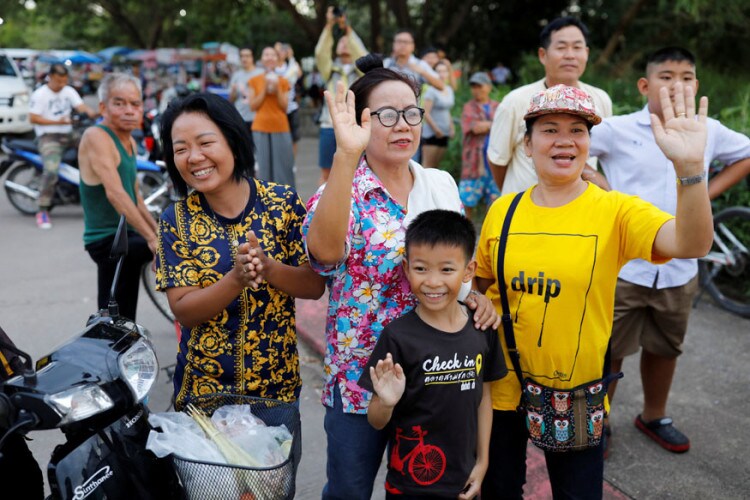 Onlookers wave as an ambulance carrying rescued schoolboys leaves a military airport in Chiang Rai