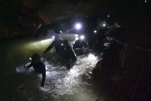 Thai rescue teams walk inside cave complex where 12 boys and their soccer coach went missing in Chiang Rai province, Thailand. (AP)