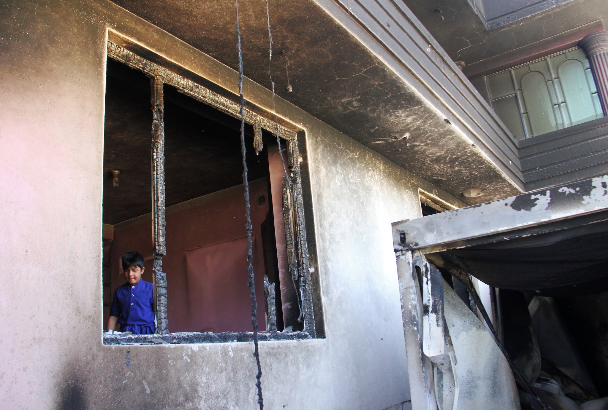An Afghan boy is seen inside a burnt building after a Taliban attack in Ghazni city, Afghanistan