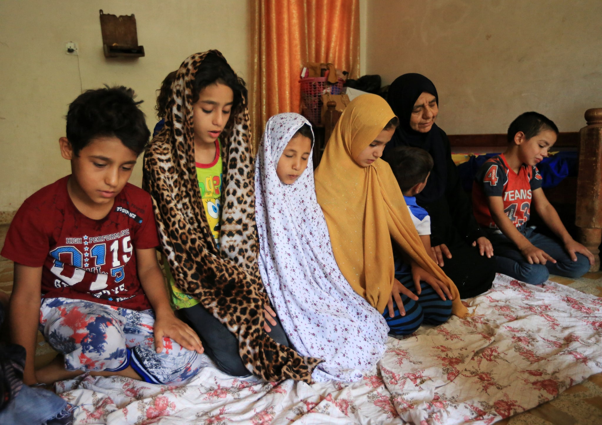 An Iraqi woman Sana Ibrahim al-Taee, 64, whose five sons were killed by Islamic State militants, pray with grandchildren at her home in Mosul, Iraq July 30, 2018. Picture taken July 30, 2018. REUTERS/Ari Jalal